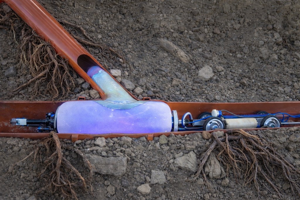 Top hat city saddle repair being installed with a trenchless sewer liner to seal a damaged lateral connection and stop sewer leaks without excavation.