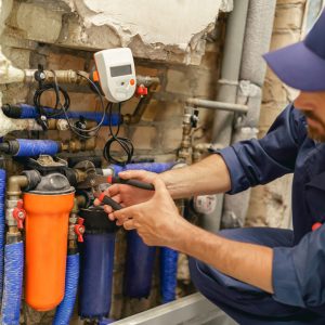 Handyman in uniform repairing water supply system at home uses an adjustable wrench